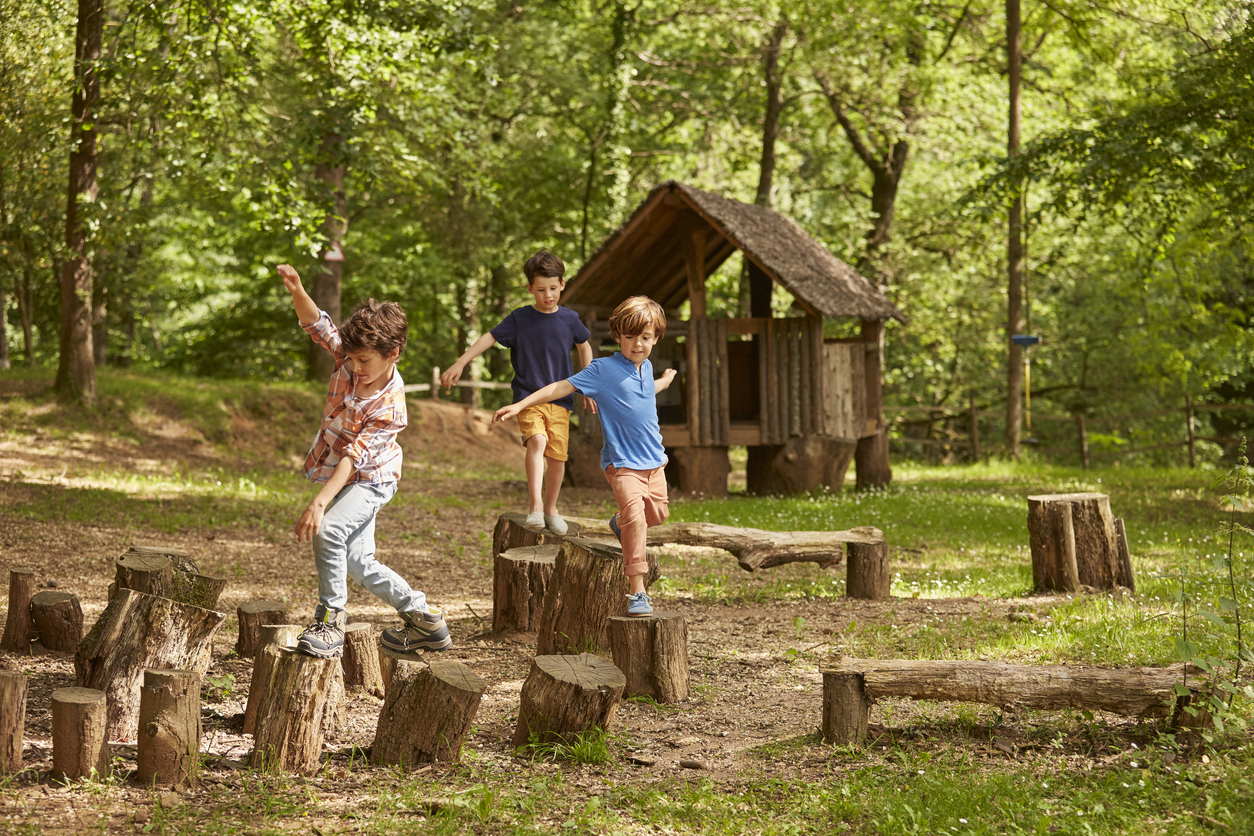 drie jongens spelen op boomstammen in een speelse en natuurrijke speeltijd